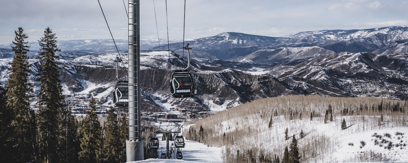 Snow covered terrain, with ski lift transporting people up the mountain hills, Aspen, Colorado.